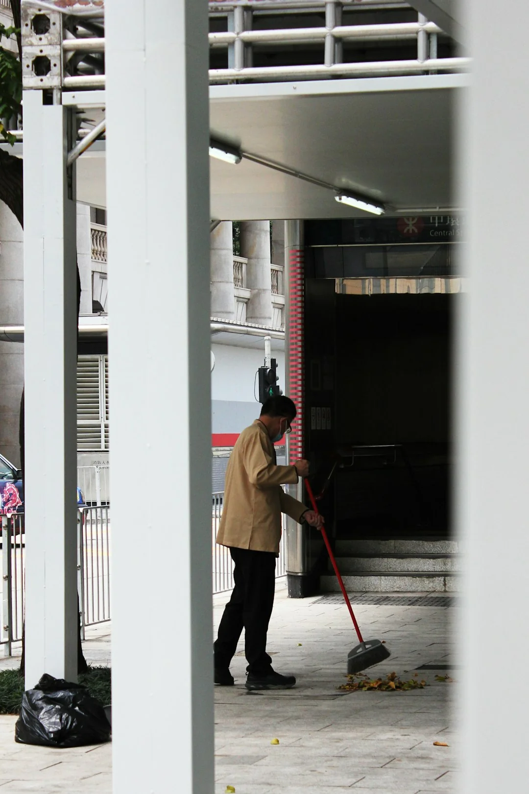 A man outdoors cleaning a glass barrier with a squeegee, surrounded by greenery.